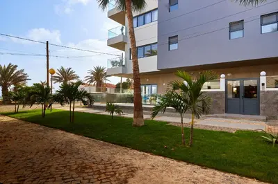 a building with palm trees in front of it at Terra Boa beach apartment Sal Cabo Verde in Santa Maria