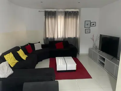 a living room with a black couch and a tv at Cozy Apartment, 3 Bedrooms in Praia