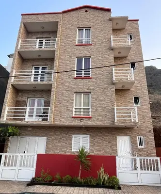 an apartment building with white doors and a red fence at Casa BB&Djassi - Apartment T3 in Ponta do Sol