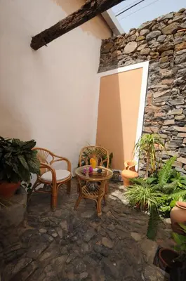 a patio with chairs and a table and a stone wall at The Colonial Guest House in São Filipe
