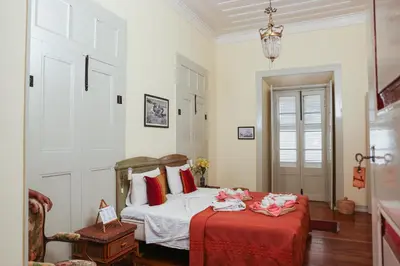 a bedroom with a bed with a red blanket at The Colonial Guest House in São Filipe