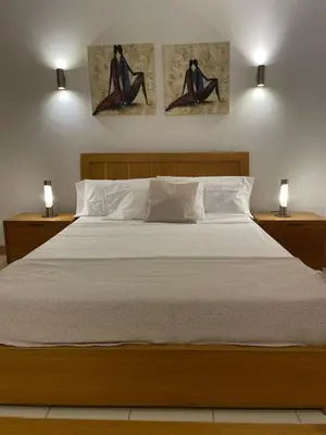 a bedroom with a bed with two paintings on the wall at Cosy 2 Bed Apartment Vila Verde Santa Maria in Santa Maria
