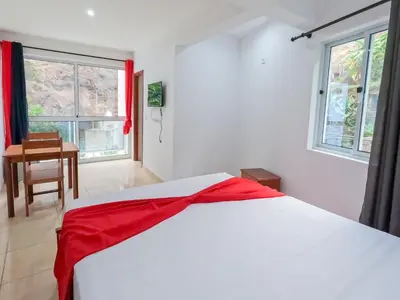 a bedroom with a white bed with a red blanket on it at Residencial Mãe Nona in Ribeira Grande