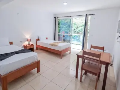 a bedroom with two beds and a desk and a window at Residencial Mãe Nona in Ribeira Grande