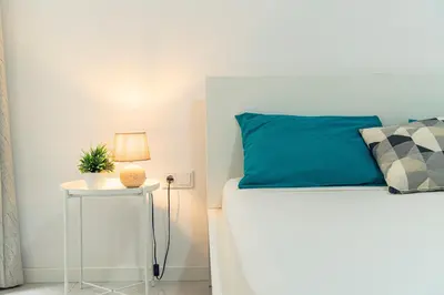 a bed with a blue pillow and a side table at 3-bdr apt 10-min walk laginha beach - LCGR in Mindelo