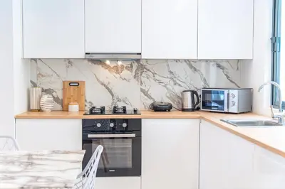 a kitchen with white cabinets and a stove top oven at 3-bdr apt 10-min walk laginha beach - LCGR in Mindelo