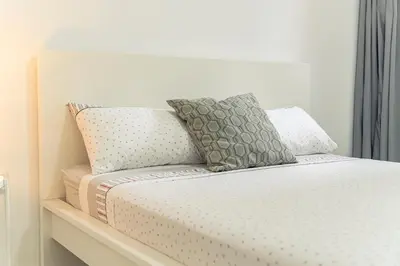 a bed with three pillows on top of it at 3-bdr apt 10-min walk laginha beach - LCGR in Mindelo
