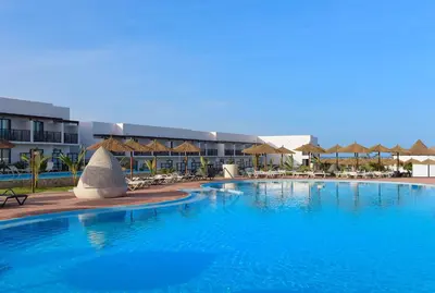 a large swimming pool with chairs and umbrellas at Meliá Laguna Beach in Santa Maria