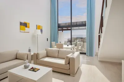 a living room with white furniture and large windows at Meliá Laguna Beach in Santa Maria