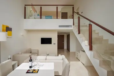 a living room with white furniture and a staircase at Meliá Laguna Beach in Santa Maria