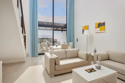 a living room with white furniture and a large window at Meliá Laguna Beach in Santa Maria