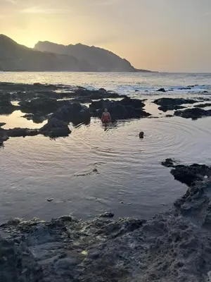 a man is in the water on the beach at Sinagoga Guesthouse in Ribeira Grande