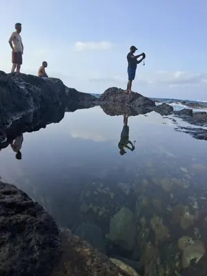 three people are standing on a rock in the water at Sinagoga Guesthouse in Ribeira Grande