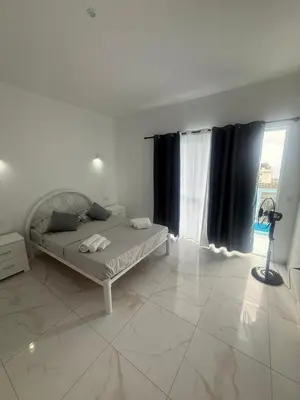 a white bedroom with a bed and a window at MeloMar Rooms in Ponta do Sol