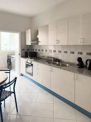 a kitchen with white cabinets and a table and chairs at 3 bdr cozy apt, Exterior POOL , Cidadela - LCGR in Praia