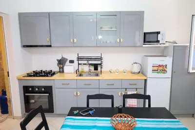 a kitchen with white cabinets and a table and a stove at 1 bedroom apartment with sofa bed 4 min walk from the beach in Santa Maria