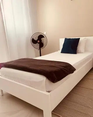 a white bed with a brown blanket and a fan at NOBRE LUZ T2 Boa Vista in Sal Rei