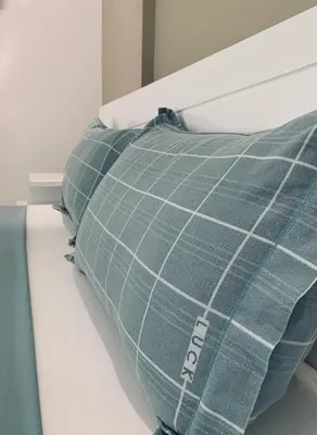 a bed with a blue plaid pillow on it at NOBRE LUZ T2 Boa Vista in Sal Rei