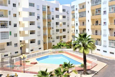an apartment building with a swimming pool and a palm tree at Mira Mar Condominium, Palmarejo Baixo in Praia