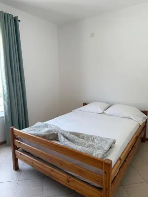 a wooden bed with white sheets and pillows at Mira Mar Condominium, Palmarejo Baixo in Praia