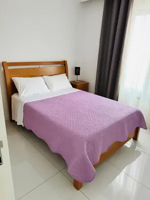 a bed with a purple blanket on it in a room at Sweet Apartment Palmarejo - Marina Residence in Praia