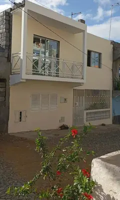 a house with a balcony and flowers in front of it at Casatata in São Filipe