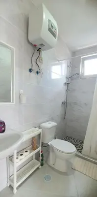a white bathroom with a toilet and a shower at Residência Alto Saco, Ocean-view double room in Tarrafal