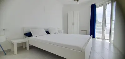 a white bedroom with a large bed and a window at Residência Alto Saco, Ocean-view double room in Tarrafal