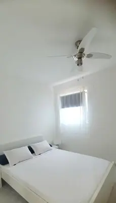 a white bed with a ceiling fan and a window at Studio Alto Saco in Tarrafal
