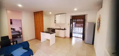 a living room with a blue couch and a kitchen at Refugio Cesaria in Tarrafal