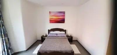 a bed in a room with a painting on the wall at Refugio Cesaria in Tarrafal