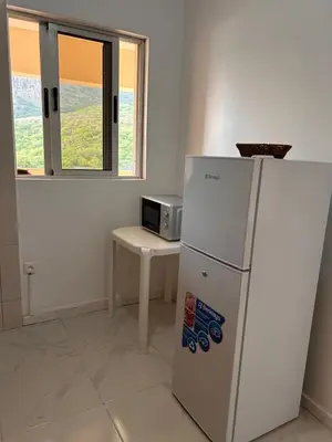 a refrigerator in a room with a table and a microwave at Sun & Sea Tarrafal in Tarrafal