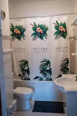 a bathroom with a shower curtain with a toilet and a sink at T2 com escritório - Férias Teletrabalho in Praia
