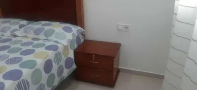 a bedroom with a bed and a wooden nightstand with a bedskirtspectspects at Lucy aparte in Praia