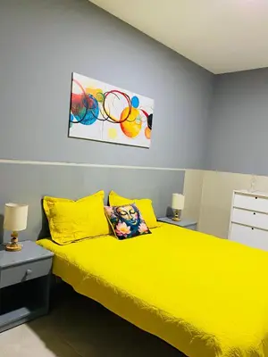 a bedroom with a yellow bed and a painting on the wall at Large 1 bedroom Apt with sofa bed in Santa Maria