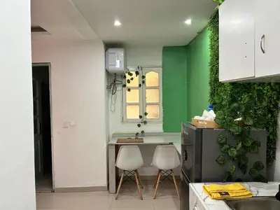 a kitchen with two white chairs and a green wall at Central 1-Bedroom Apartment near Sucupira Market in Praia
