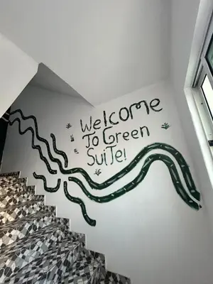 a wall with a staircase with a welcome to green smile mural at Central 1-Bedroom Apartment near Sucupira Market in Praia