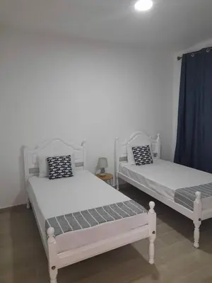 two white beds in a room with blue curtains at Tarrafal snuggle in Tarrafal