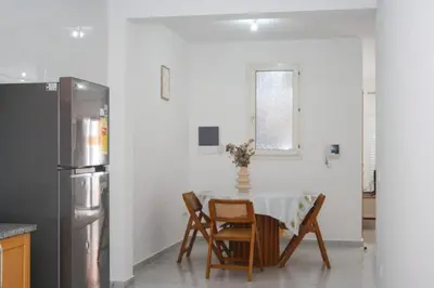 a kitchen with a table with chairs and a refrigerator at Rooms in Apartment Morabeza in Praia Cidadela in Praia
