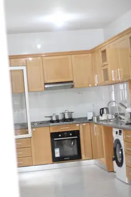 a kitchen with wooden cabinets and a stove top oven at Rooms in Apartment Morabeza in Praia Cidadela in Praia