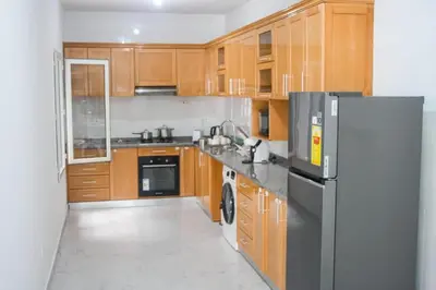 a kitchen with wooden cabinets and a stainless steel refrigerator at Rooms in Apartment Morabeza in Praia Cidadela in Praia