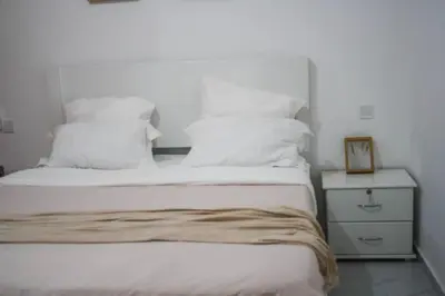 a bedroom with a bed with white pillows and a night stand at Rooms in Apartment Morabeza in Praia Cidadela in Praia