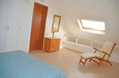 a bedroom with a bed and a chair and a mirror at Stunning, spacious penthouse in beach front Leme Bedje Residence in Santa Maria