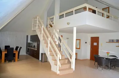 a staircase in a living room with a table and chairs at Stunning, spacious penthouse in beach front Leme Bedje Residence in Santa Maria