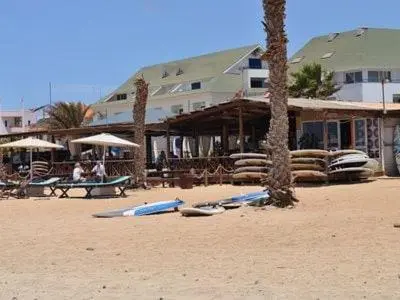a beach with a building and a bunch ofogie boards at Stunning, spacious penthouse in beach front Leme Bedje Residence in Santa Maria