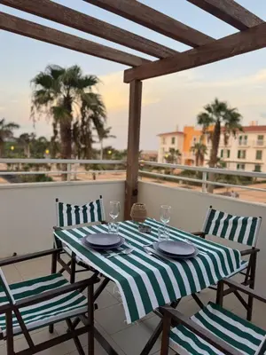 a table and chairs on a balcony with palm trees at Vila Verde Lantana B103 by RPG Group in Santa Maria