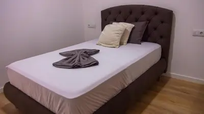 a bed with a black headboard and a robe on it at Domus Lima in Mindelo