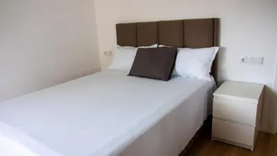 a bedroom with a large white bed with a brown headboard at Domus Lima in Mindelo