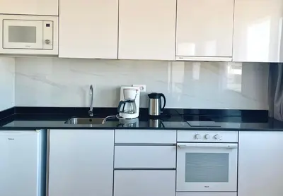 a kitchen with white cabinets and a coffee maker on the counter at Apartamento T1 - MedSal Residence in Santa Maria
