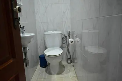 a white bathroom with a toilet and a sink at Cozy Palm in Praia